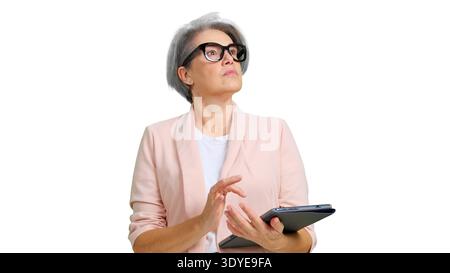Donna matura che guarda in alto reggendo un tablet digitale Foto Stock