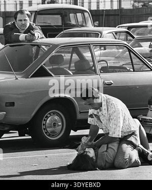 Questa foto di grande impatto del 1973 di Huynh Cong "Nick" Ut cattura una scena drammatica durante un tentativo di rapimento, mostrando un uomo che tiene una donna sul marciapiede mentre un altro uomo, una guardia di sicurezza, punta una pistola sopra un'auto. L'immagine è una rappresentazione grezza di un evento violento che si è svolto a Hollywood. Faceva parte del corpo di lavoro che gli valse il Premio Pulitzer. Foto Stock