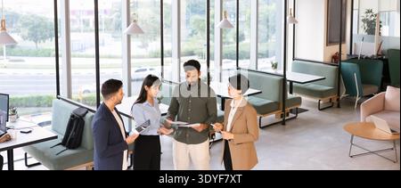 Diversi professionisti che collaborano alla documentazione cartacea e al tablet digitale in ufficio Foto Stock
