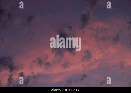 Il cielo viola arrossisce di rosa mentre le nuvole si spostano. Le tonalità morbide si fondono nella calma del crepuscolo. Ideale per temi sereni, tranquilli o romantici. Perfetto per l'umore Foto Stock