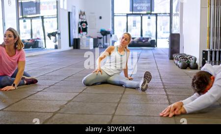 Persone che si allungano in una classe di gruppo praticando fitness e flessibilità Foto Stock