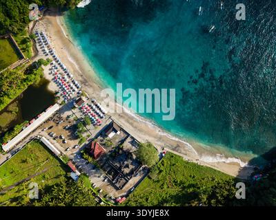 Prospettiva dall'alto verso il basso di ombrelloni colorati, spiaggia di sabbia e barche a Crystal Bay, Bali Foto Stock