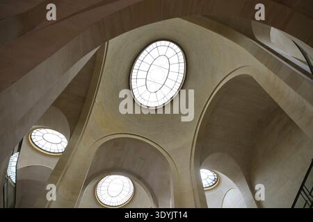 Parigi, Francia - 4 ottobre 2025: Vista ad angolo basso dei moderni archi in pietra e dei lucernari circolari all'interno del seminterrato del Museo del Louvre Foto Stock