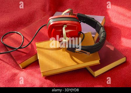 concetto audiok con una pila di libri e cuffie vintage Foto Stock