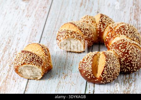 Panini di pretzel appena sfornati con primo piano di semi di sesamo. Pasticceria tradizionale tedesca, austriaca o svizzera su fondo in legno con spazio per copiare Foto Stock