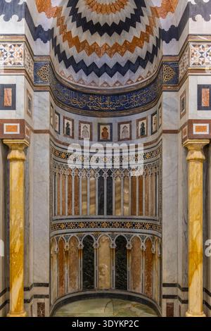 Elaborato mihrab islamico e interni decorati della moschea con intarsi in marmo, calligrafia araba e lampade a sospensione nella storica città del Cairo, in Egitto, showcasi Foto Stock