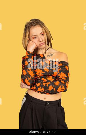 Giovane donna con dreadlock che riposa il mento sulla mano, sembra penosa e annoiata Foto Stock