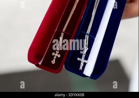 Primo piano di due collane di crocifissi in casse rosse e blu preparate per il rito del battesimo in chiesa simboli religiosi di fede cristiana gioielli per ne Foto Stock