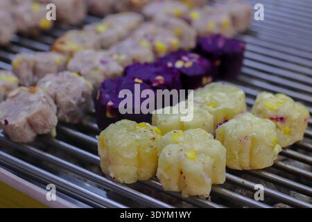 Dolci tradizionali thailandesi a base di patate dolci, cottura lenta su una griglia a carbone, autentico cibo di strada artigianale con vivaci colori naturali a base di piante. Foto Stock