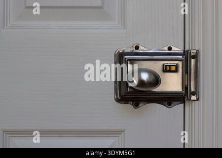 Una serratura e una maniglia tradizionali su una porta bianca intelligente in una casa Foto Stock