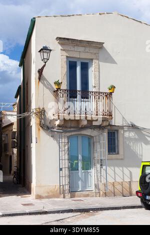 Una facciata bianca di un tradizionale edificio sul mare, con un'auto 4x4 parcheggiata di fronte ad esso Foto Stock