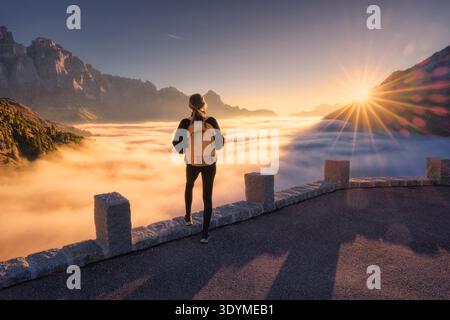 Donna in piedi sopra le nuvole al tramonto nelle Alpi svizzere Foto Stock
