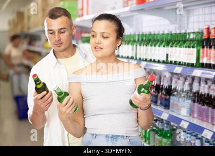 Coppia positiva che sceglie bevande alcoliche al negozio asiatico locale Foto Stock