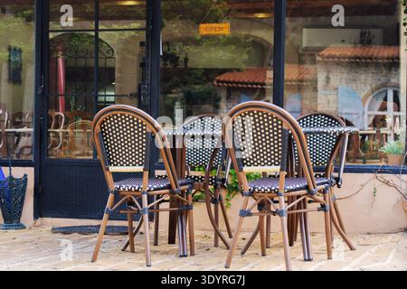 Tavoli e sedie da caffè all'aperto. Terrazza caffetteria esterna vuota con sedie e tavoli in rattan, sfondo urbano. Foto Stock