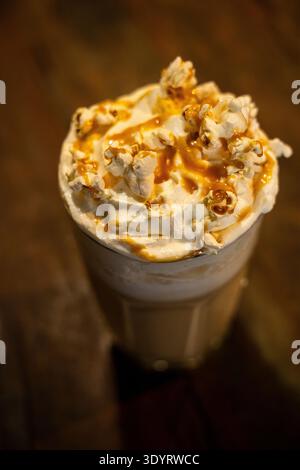 Primo piano di una bevanda a base di caffè creativa e appagante. Il latte freddo viene servito in un bicchiere alto, abbondantemente condito con panna montata, panna dolce Foto Stock
