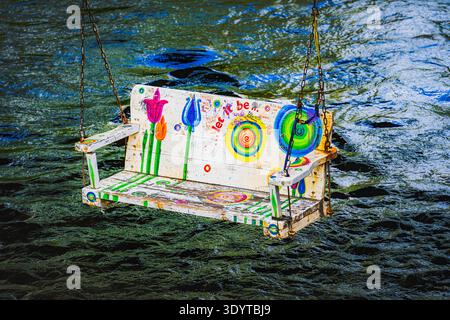 La famosa "Swing of Destiny" dipinta con fiori colorati e la frase "Let IT Be", sospesa sul fiume Vilnia a Užupis, Vilnius. Foto Stock