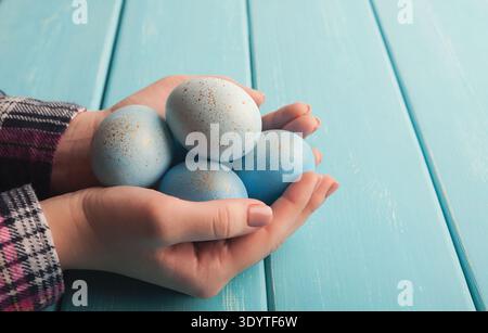 Donna che mantiene colorate in blu le uova di pasqua su tavole di legno Foto Stock