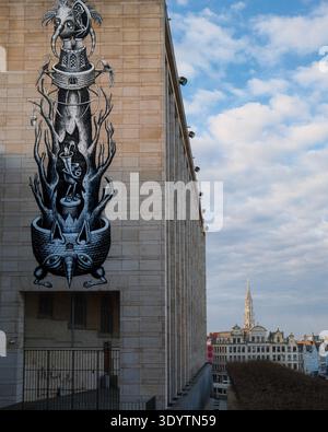 Un grande murale di Street art monocromatico sul lato di un edificio vicino a Place Royale, con la guglia gotica del Municipio di Bruxelles visibile. Foto Stock