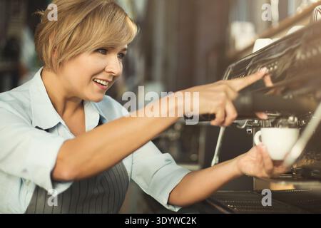 Barista esperto che prepara il caffè con una macchina da caffè professionale Foto Stock