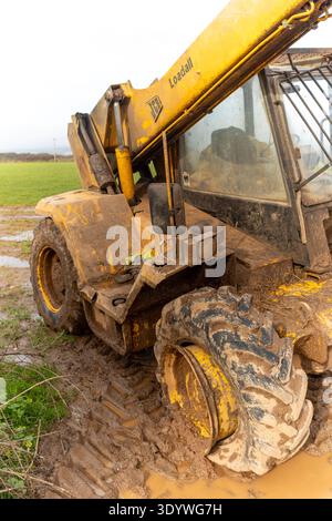Macchina JCB bloccata su un terreno fangoso con pneumatico sgonfiato Foto Stock