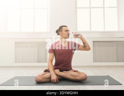 Fitness man che beve acqua in palestra Foto Stock