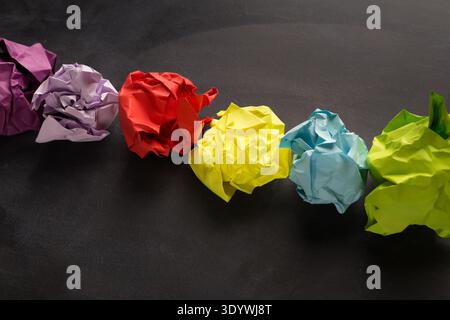 Palline di carta multicolore sgualcite su sfondo nero Foto Stock
