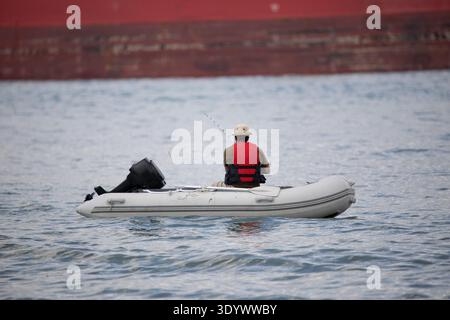 Pescatore in barca in una zattera con canna da pesca Foto Stock