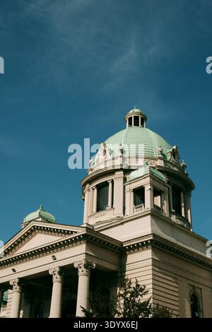 Vista ravvicinata della cupola verde e dell'architettura classica dell'edificio dell'Assemblea nazionale contro un cielo blu terso a Belgrado. Foto Stock