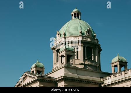 Vista ravvicinata della cupola verde e dell'architettura classica dell'edificio dell'Assemblea nazionale contro un cielo blu terso a Belgrado. Foto Stock