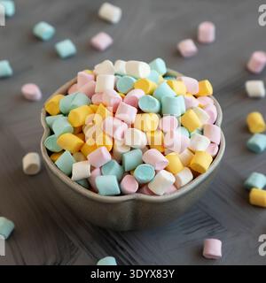 Mini marshmallow multicolore malsani in una ciotola, vista laterale. Foto Stock