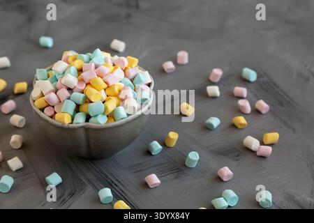 Mini marshmallow multicolore malsani in una ciotola, vista laterale. Foto Stock