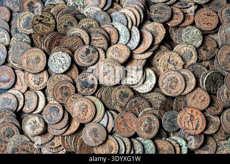 Un'immagine full-frame ad alto angolo di una fitta collezione di antiche monete romane in bronzo. Le monete mostrano un'usura significativa, con consistenze visibili di ossidazione Foto Stock