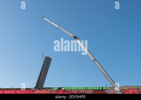 la grande gru mobile solleva l'isolamento del tetto su uno sfondo blu Foto Stock