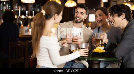 Gruppo di giovani amici felici che si divertono insieme nel pub della birra Foto Stock