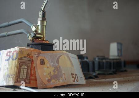 Concetto finanziario che mostra una banconota da 50 euro su un'unità di stoccaggio dell'olio. Rappresenta la pressione inflazionistica sulle materie prime energetiche e la perdita di acquisti Foto Stock