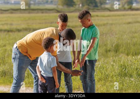 Un padre spruzza repellente per insetti sul bambino prima di fare escursioni con la famiglia in campagna per prevenire le zanzare e le punture di zecche. Foto Stock