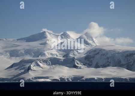 Vista delle alte montagne innevate avvolte da nuvole, della penisola Antartica e dell'Antartide Foto Stock