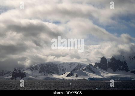 Vista pittoresca delle montagne alte, aspre e innevate e delle dense nuvole, della penisola Antartica e dell'Antartide Foto Stock