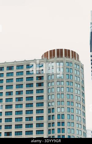 Un alto edificio con una cima rotonda presenta molte finestre e si erge contro un cielo nuvoloso durante il giorno in una città. Foto Stock