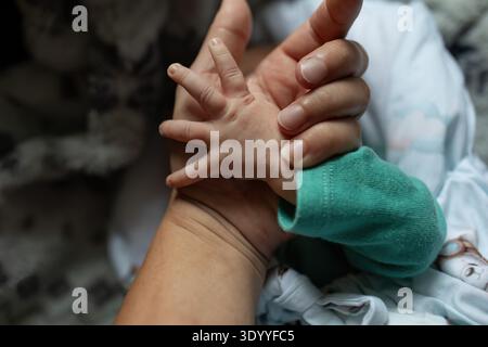 Neonato con dito del genitore primo piano Foto Stock