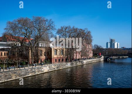 Scena lungo il fiume a Berlino con colorati edifici storici, alberi senza foglie, pedoni e moderni grattacieli sullo sfondo in una giornata d'inverno limpida. Foto Stock