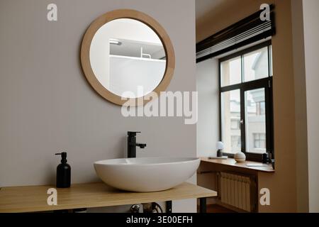 Interni moderni del bagno con specchio rotondo e design minimalista del lavandino Foto Stock