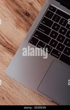 Vista dall'alto pulita di una tastiera argentata per laptop e di un trackpad appoggiati su una scrivania in legno di colore chiaro, ideale per un ufficio domestico minimalista. Foto Stock