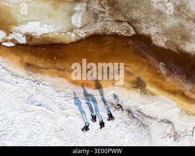 Vista aerea dall'alto verso il basso delle persone che si trovano su un piccolo fondo di ghiaccio circondato da acqua fangosa del fiume, concetto di rischio e impatto del riscaldamento globale. Alta qualità p Foto Stock