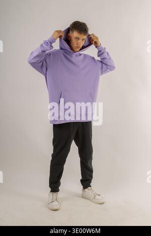 Bel giovane ragazzo in abiti eleganti su sfondo bianco in uno studio fotografico che posa per la fotocamera Foto Stock