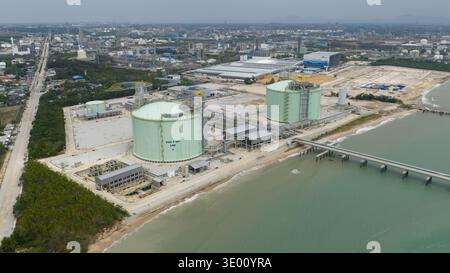 Vista aerea di enormi serbatoi di GNL risplendono sullo sfondo di strutture industriali lungo la costa, MAP Ta Phut, Rayong, Thailandia. Foto Stock