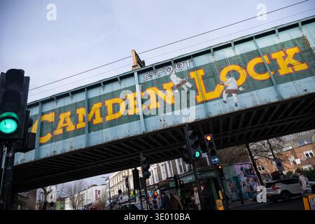 Vista del famoso ponte ferroviario di Camden Lock con il suo simbolo dipinto a mano, che si estende su Chalk Farm Road nel cuore del mercato di Camden Foto Stock