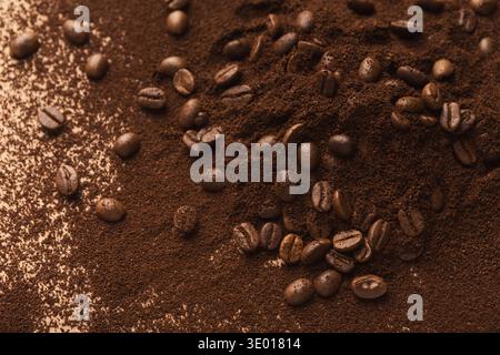 Un mucchio di chicchi di caffè scuri e semi tostati macinati Foto Stock