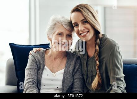 Ritratto, abbraccio e figlia con la madre anziana in salotto, sorridere e legarsi insieme per una pausa. Famiglia, abbraccio e donne sul divano, felicità e.. Foto Stock