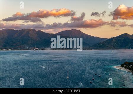 Vista ad alto angolo della costa tropicale con barche, acqua blu e catena montuosa lontana Foto Stock